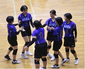 体育館でバレーボールの試合に臨む女子生徒たちの写真