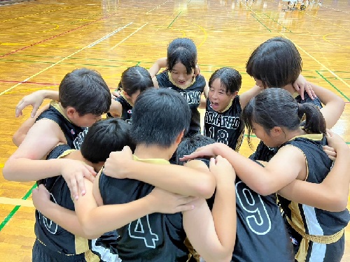 体育館でバスケットボールチームが円陣を組んで気合を入れている写真