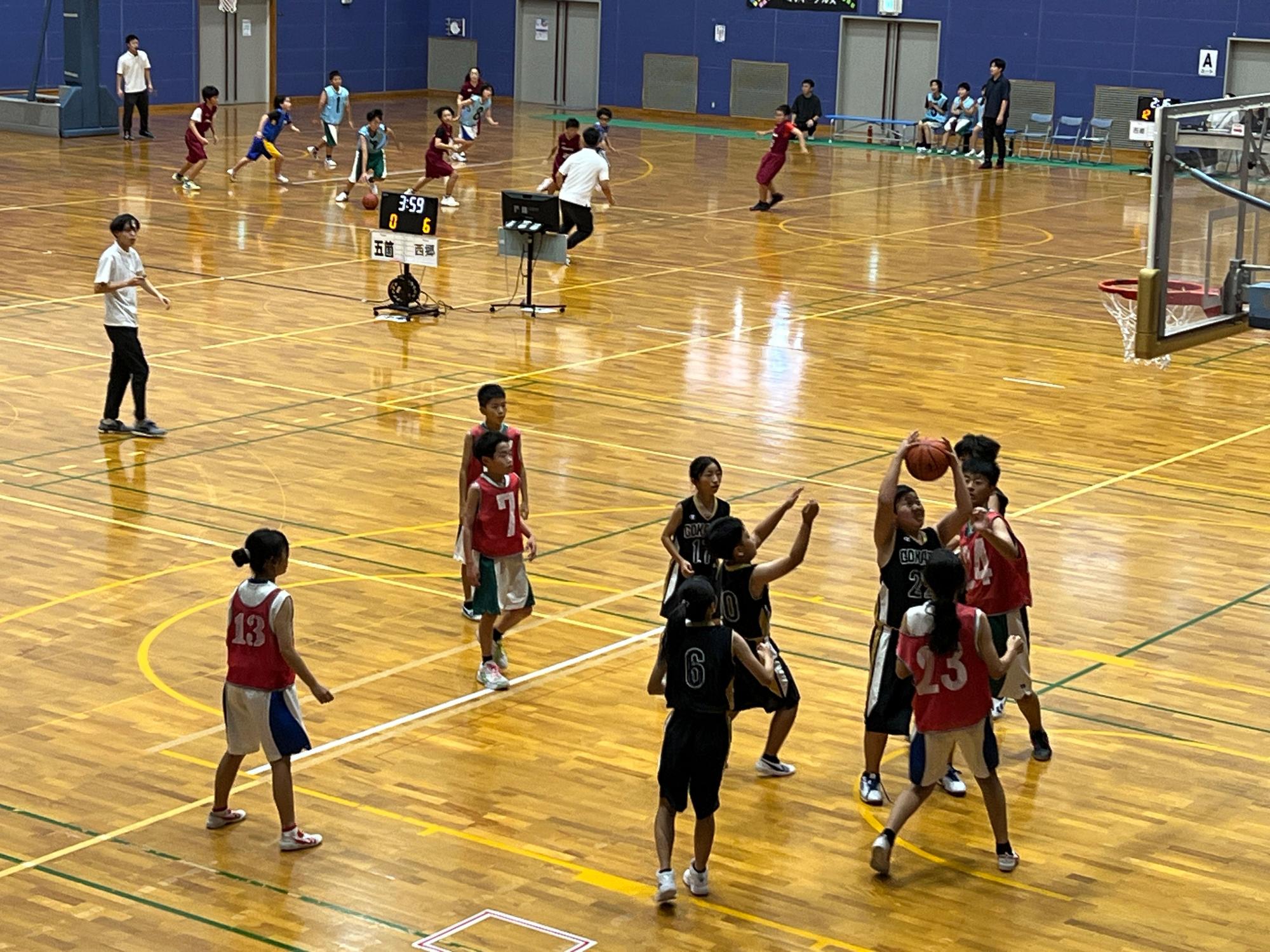 体育館で児童たちがバスケットボールの試合をしている写真