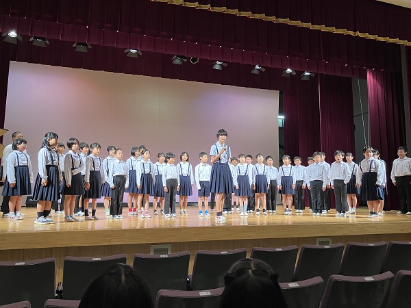 発表会で児童たちがステージ上で合唱をしている写真