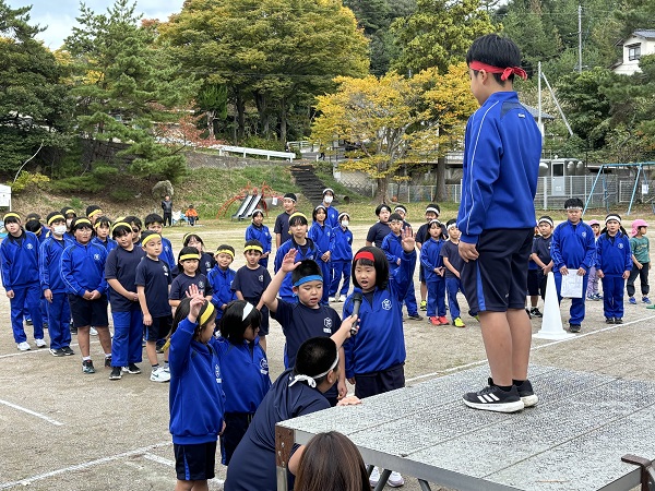 外で4人の児童が1人の児童に対して選手宣誓を行っている様子の写真