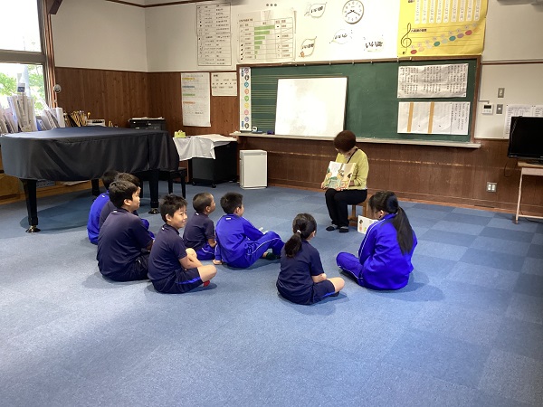 教室で児童たちが先生の読み聞かせを聞いている写真