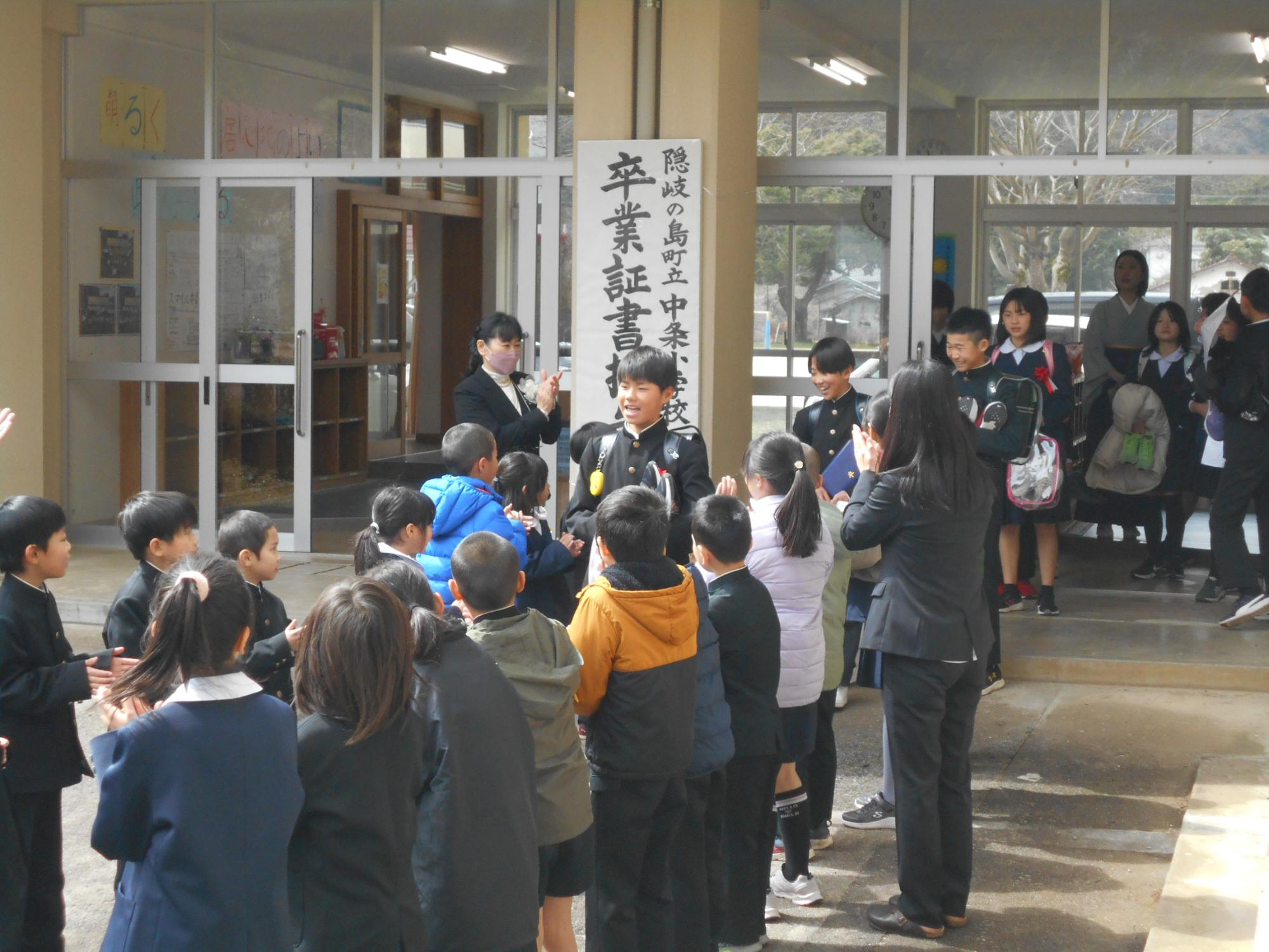 校舎の玄関前で在校生が卒業生を見送っている写真