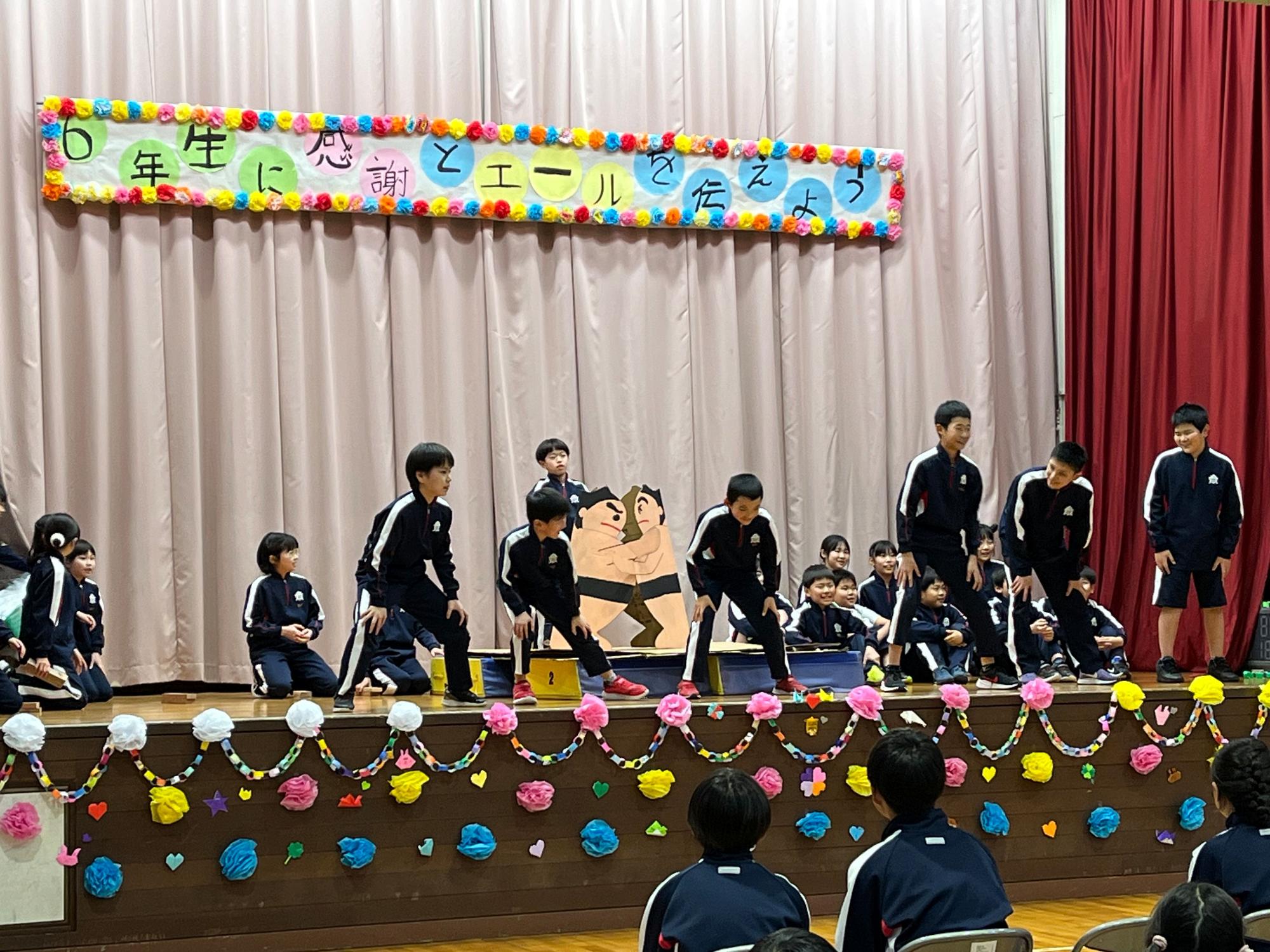 体育館の舞台で児童たちが発表をしている写真