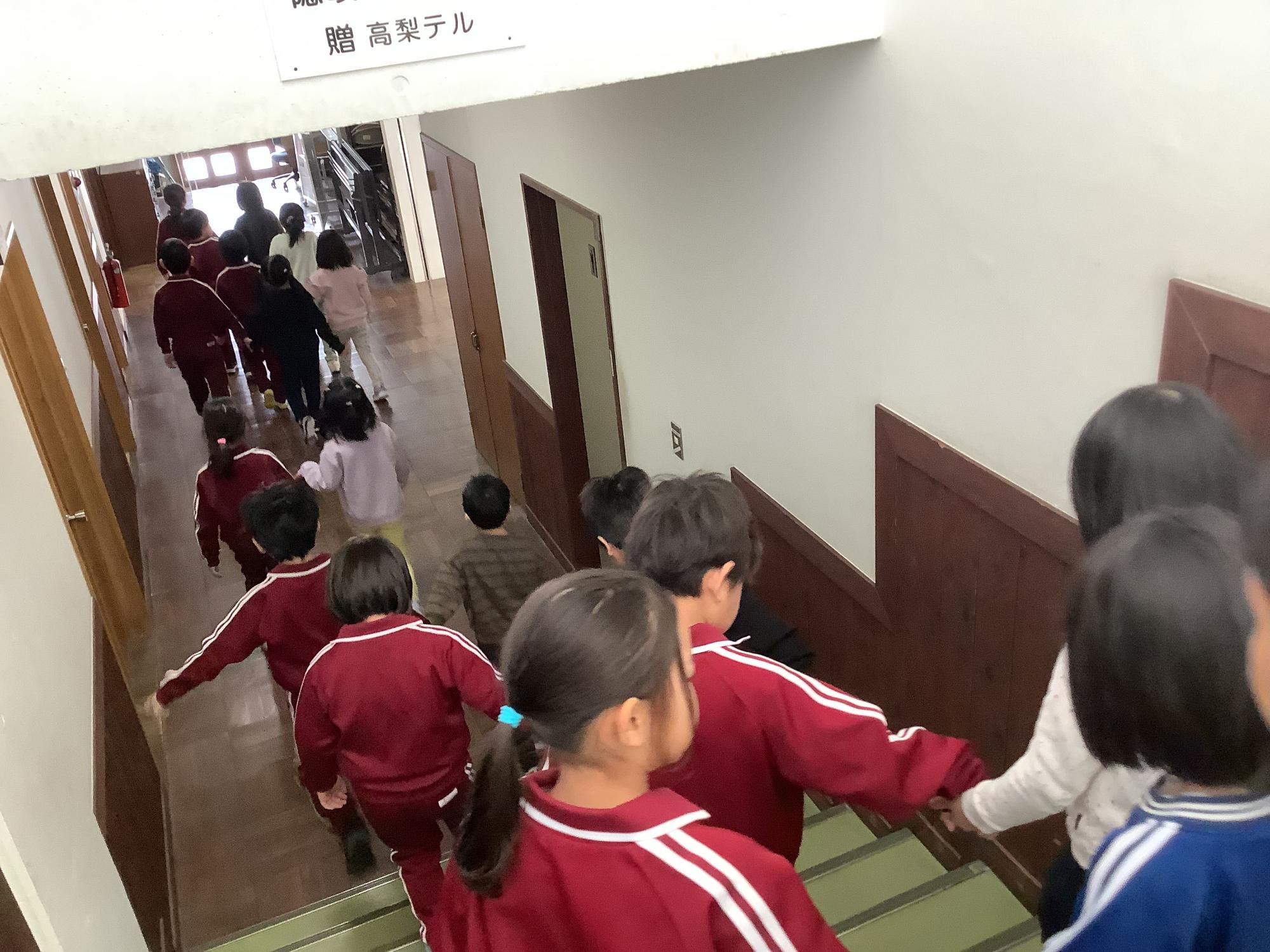 ジャージを着た児童たちが列になって階段を下りている写真