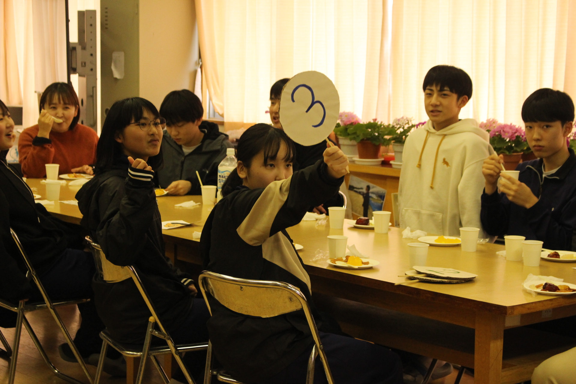 教室で生徒たちが食事を楽しみながらクイズ大会をしている写真