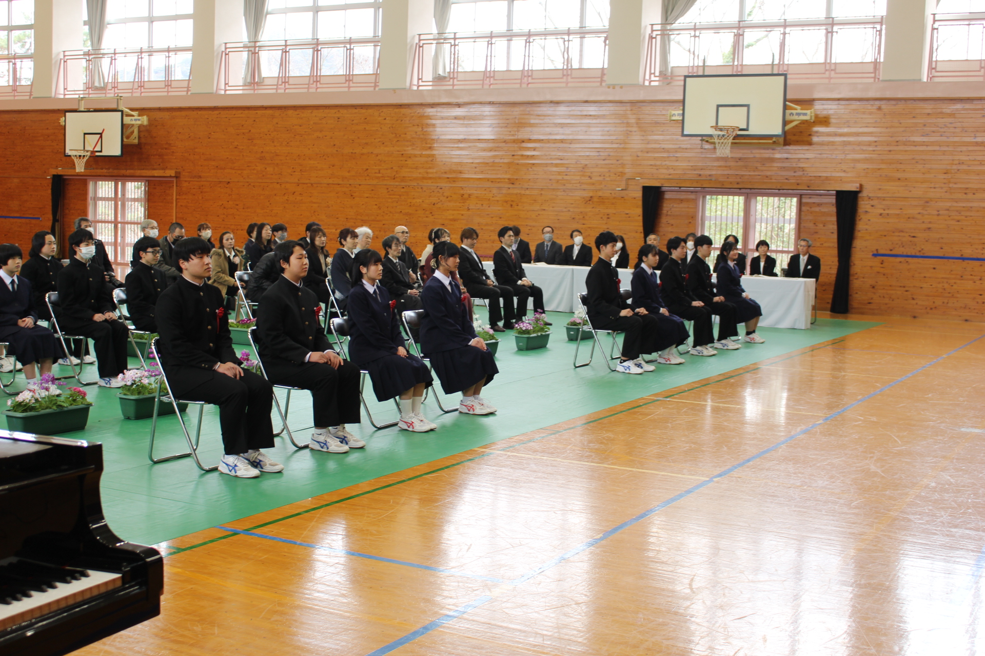 体育館で卒業式に出席する生徒と保護者が整列している写真