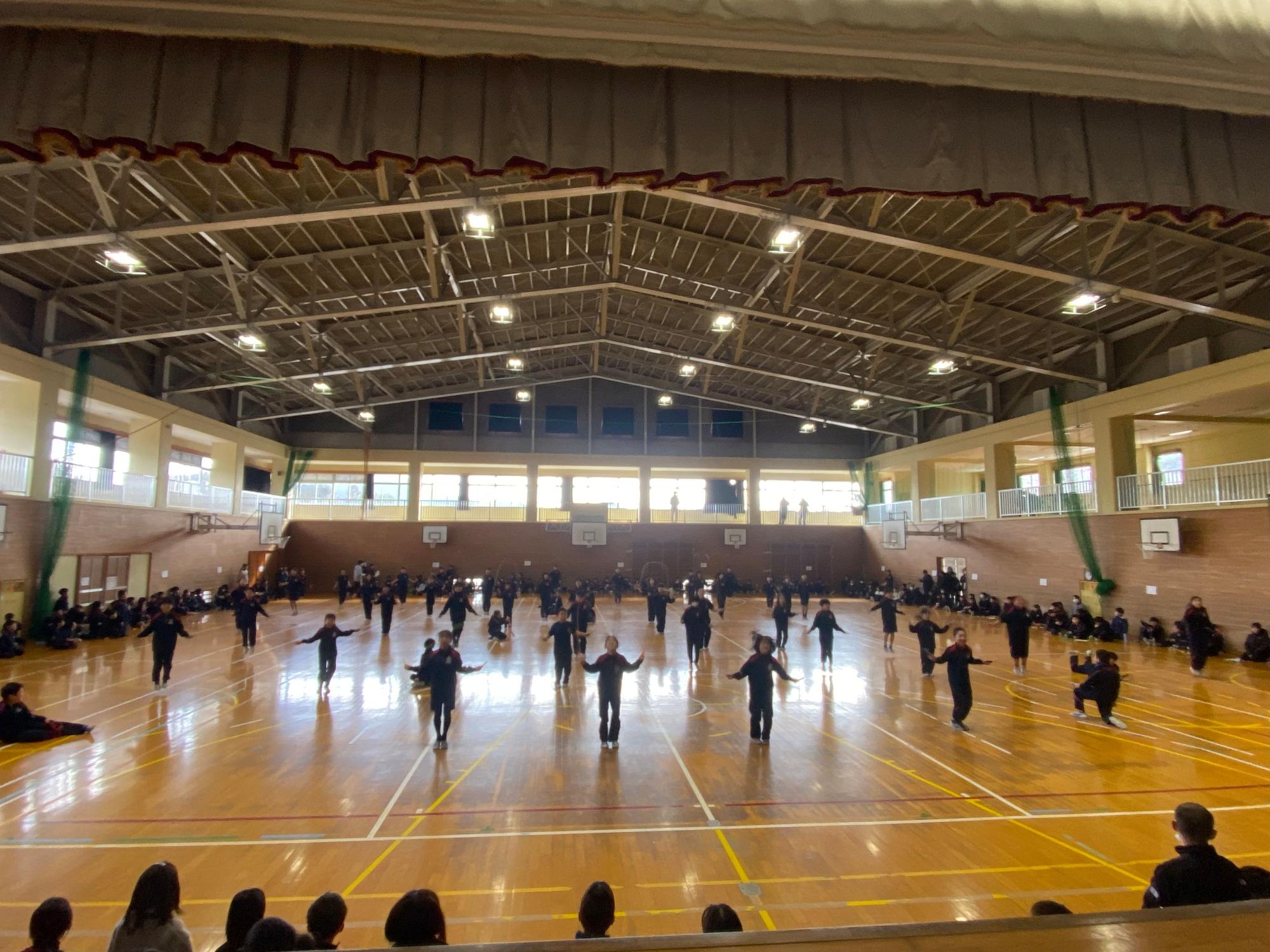 体育館で児童たちが体を動かして発表している写真