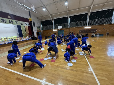 体育館で複数の子どもたちがしゃがみながら屋内用のゲームをしている写真
