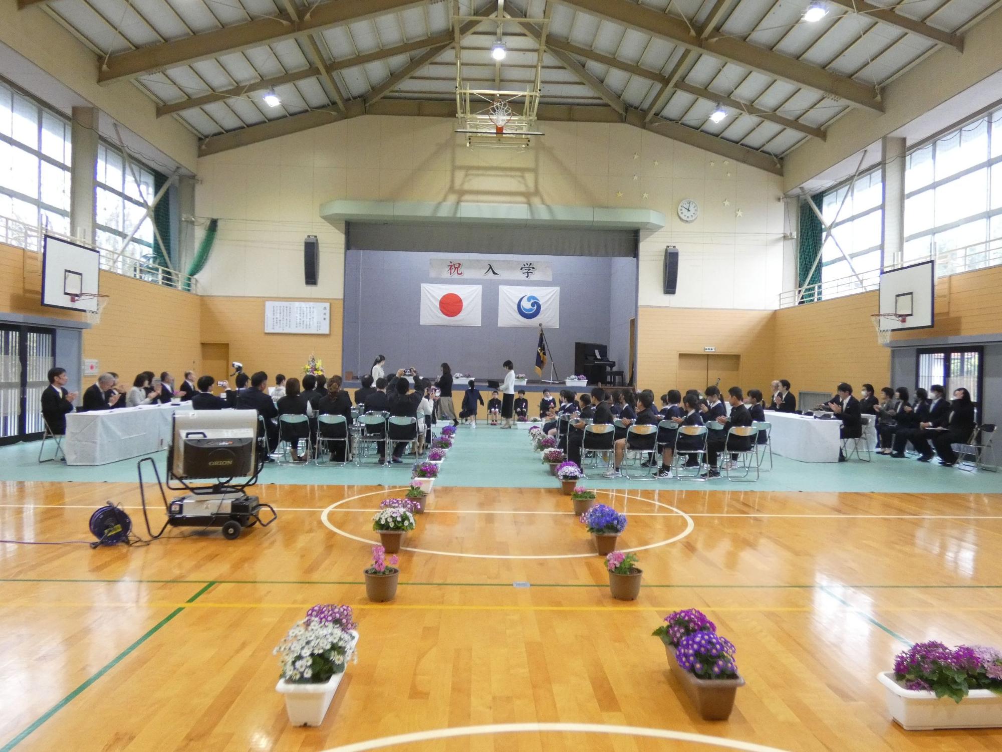 体育館で新入生を迎える入学式が行われている様子を正面から撮影した写真