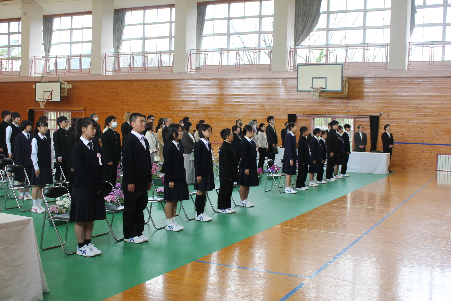 体育館で生徒と保護者が整列し入学式が行われている写真