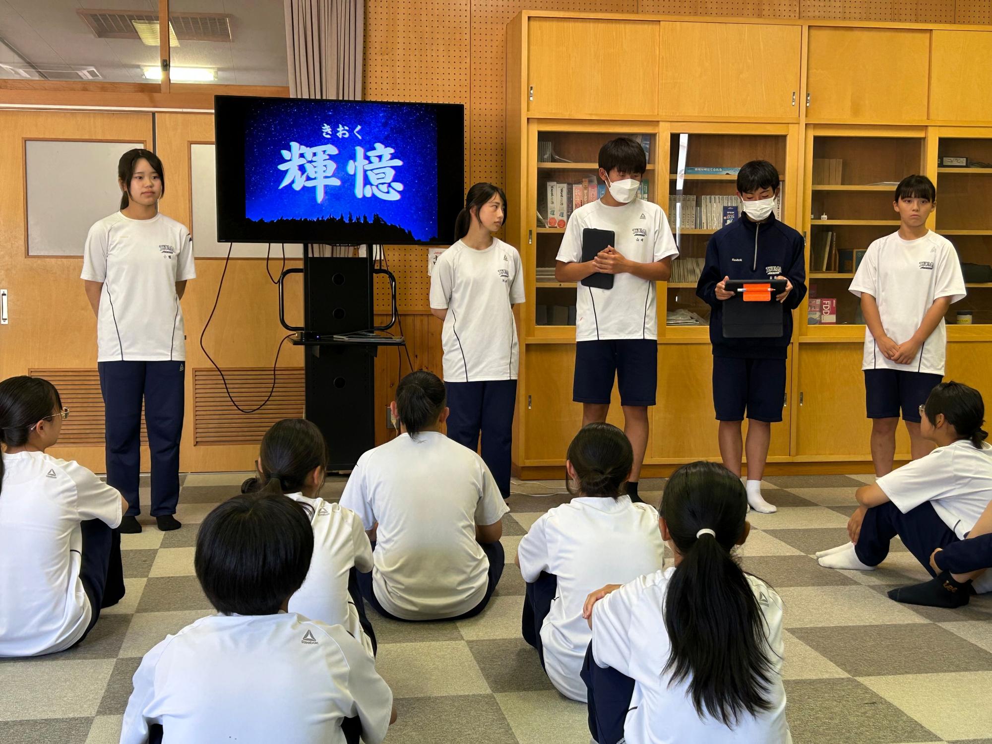 教室で前に立った生徒たちがモニターを使って発表を行っている写真