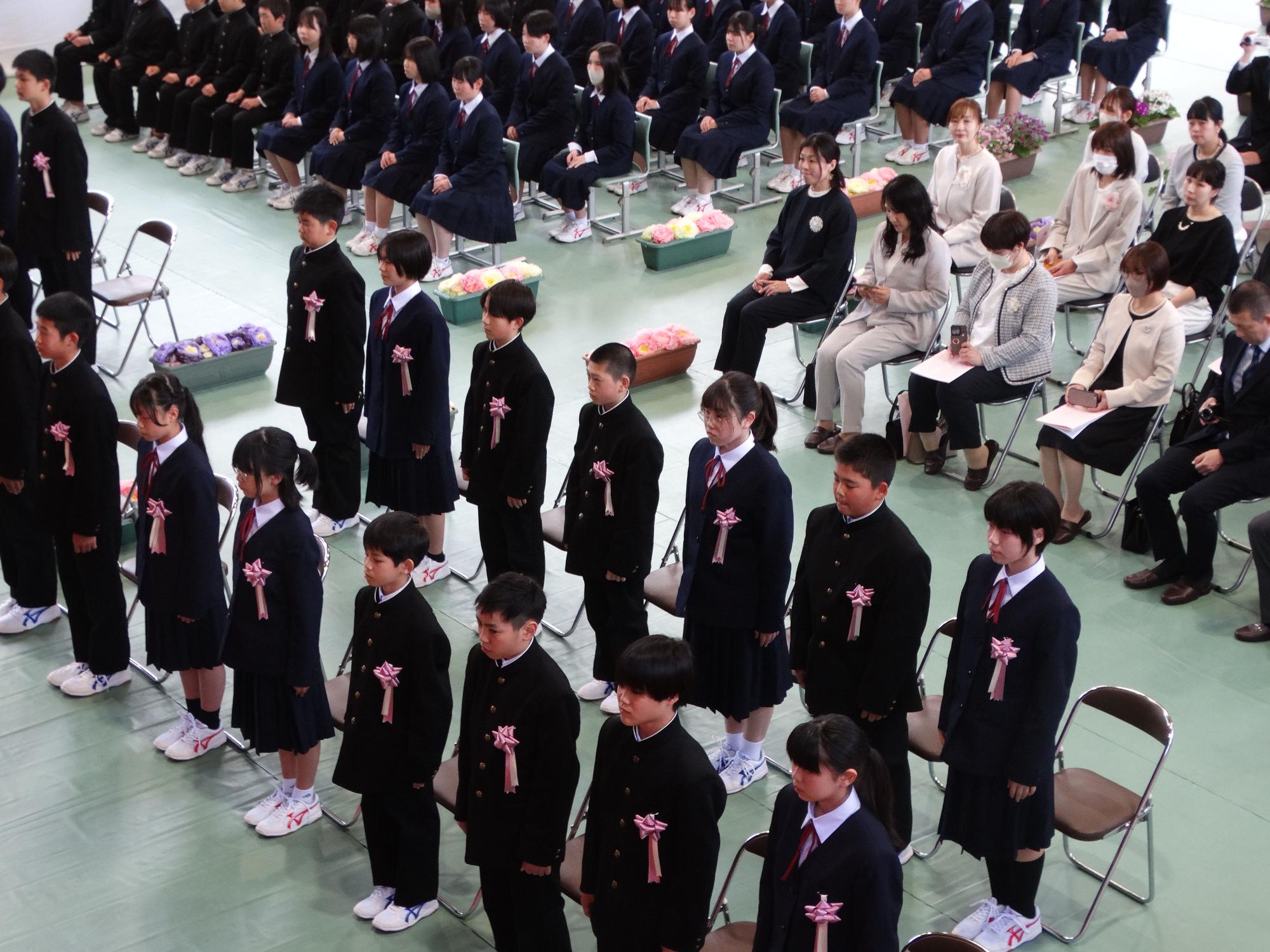 体育館で生徒たちが整列して入学式に参加している写真