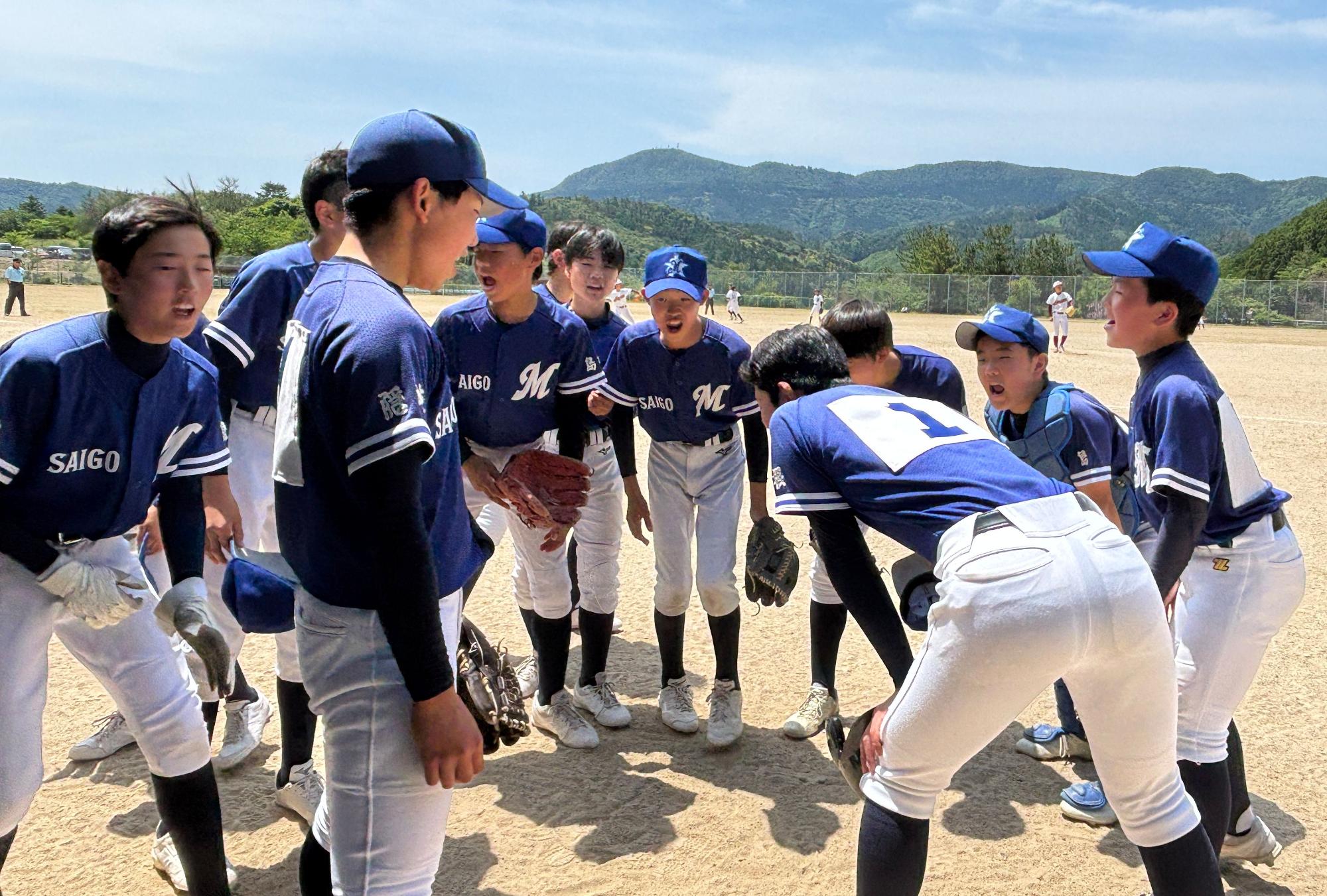 グラウンドでユニフォームを着た野球部の男子生徒たちが円陣を組んでいる写真