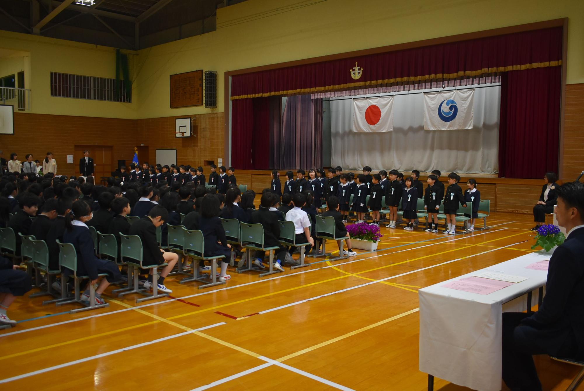 体育館で新入生が並んで入学式に参加している写真