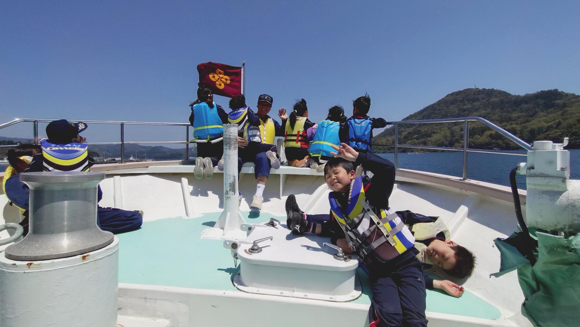 船の上でライフジャケットを着た子どもたちが笑顔でポーズをしている写真