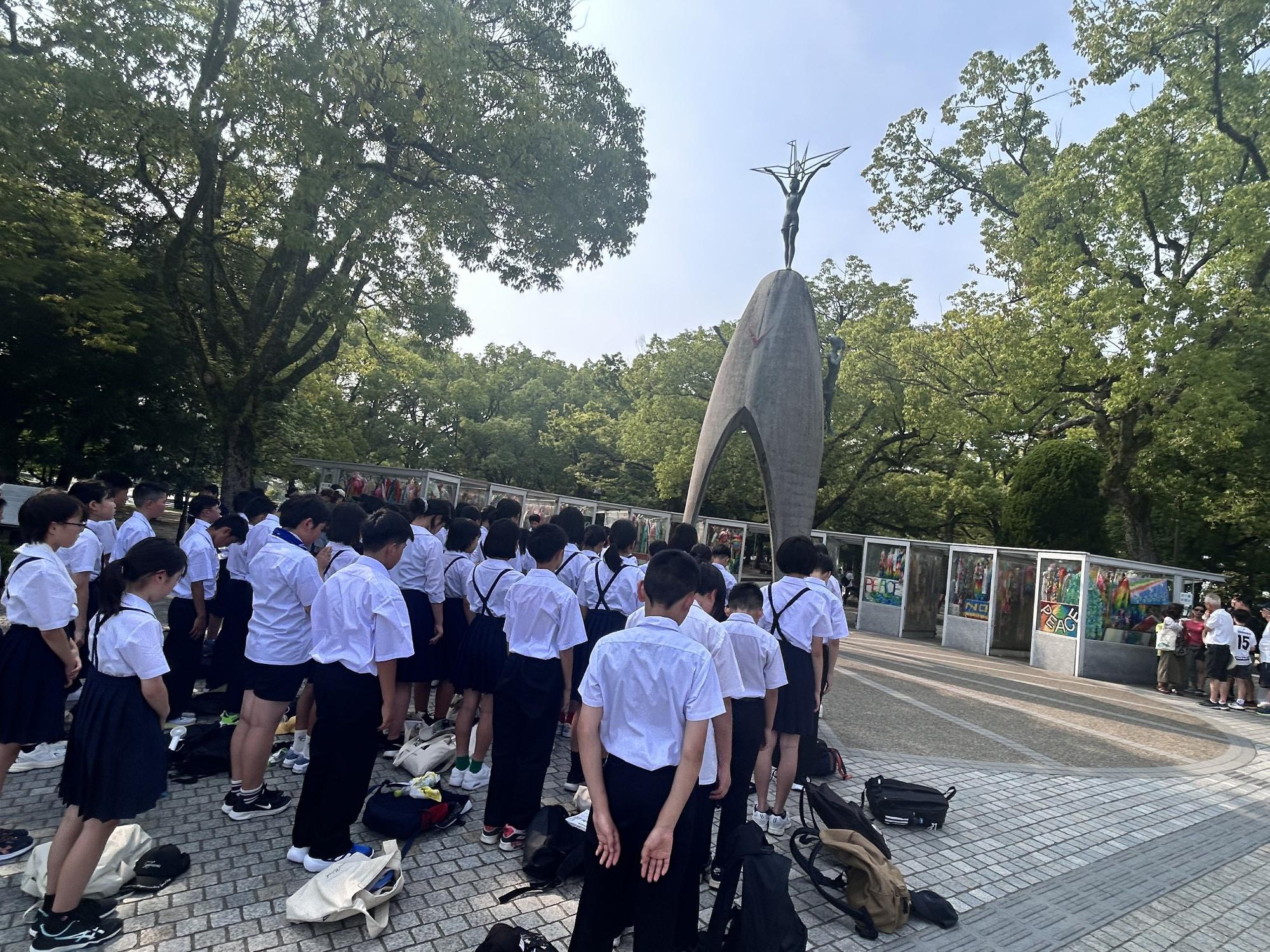 平和記念公園で子供たちが慰霊碑の前で黙とうしている写真