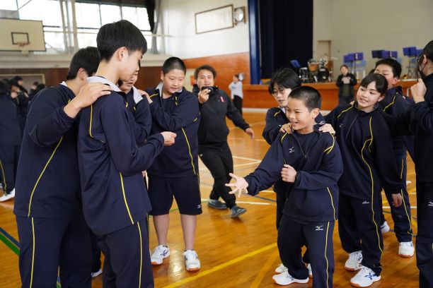 体育館でジャージを着た生徒たちが集まってじゃんけんをしている写真