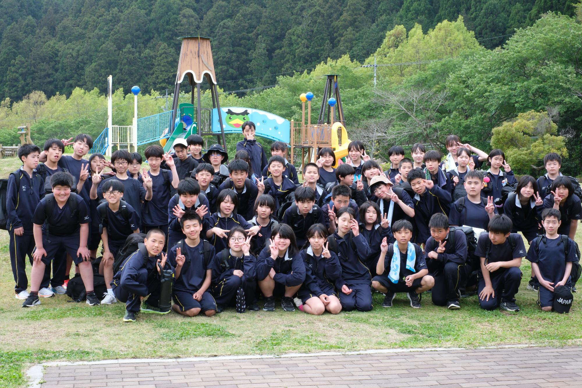 公園で多くの生徒たちが集合して記念撮影をしている写真