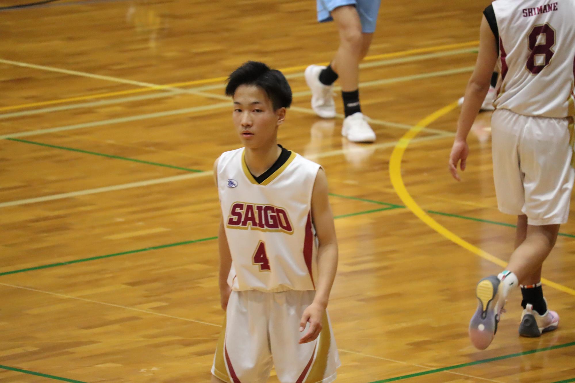 体育館でバスケットボールのユニフォームを着た生徒が試合に臨んでいる写真