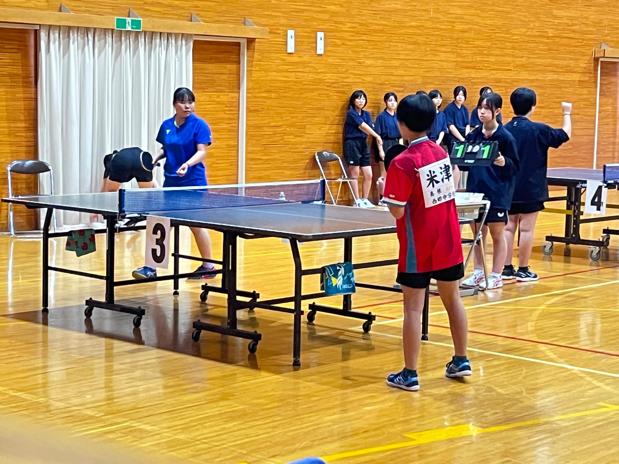 体育館で卓球の試合をしている生徒たちの写真