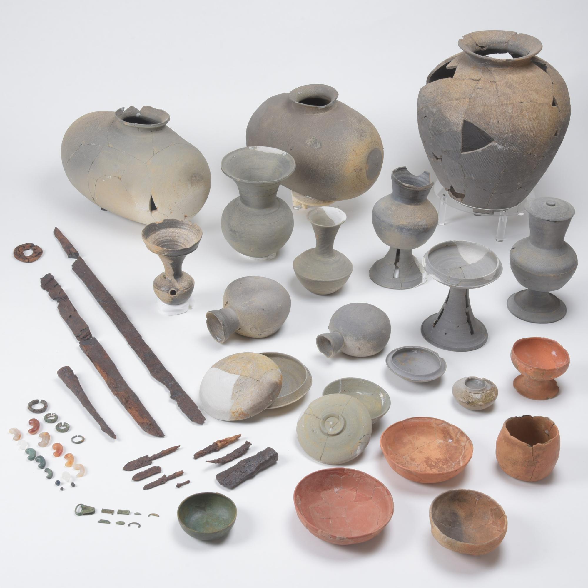 様々な形や大きさの土器、金属製品、装飾品等が並んでいる大座西古墳群出土品の写真