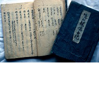 表紙の見える一冊と、開かれている一冊が並んでいる、佐々木家庄屋文書の写真