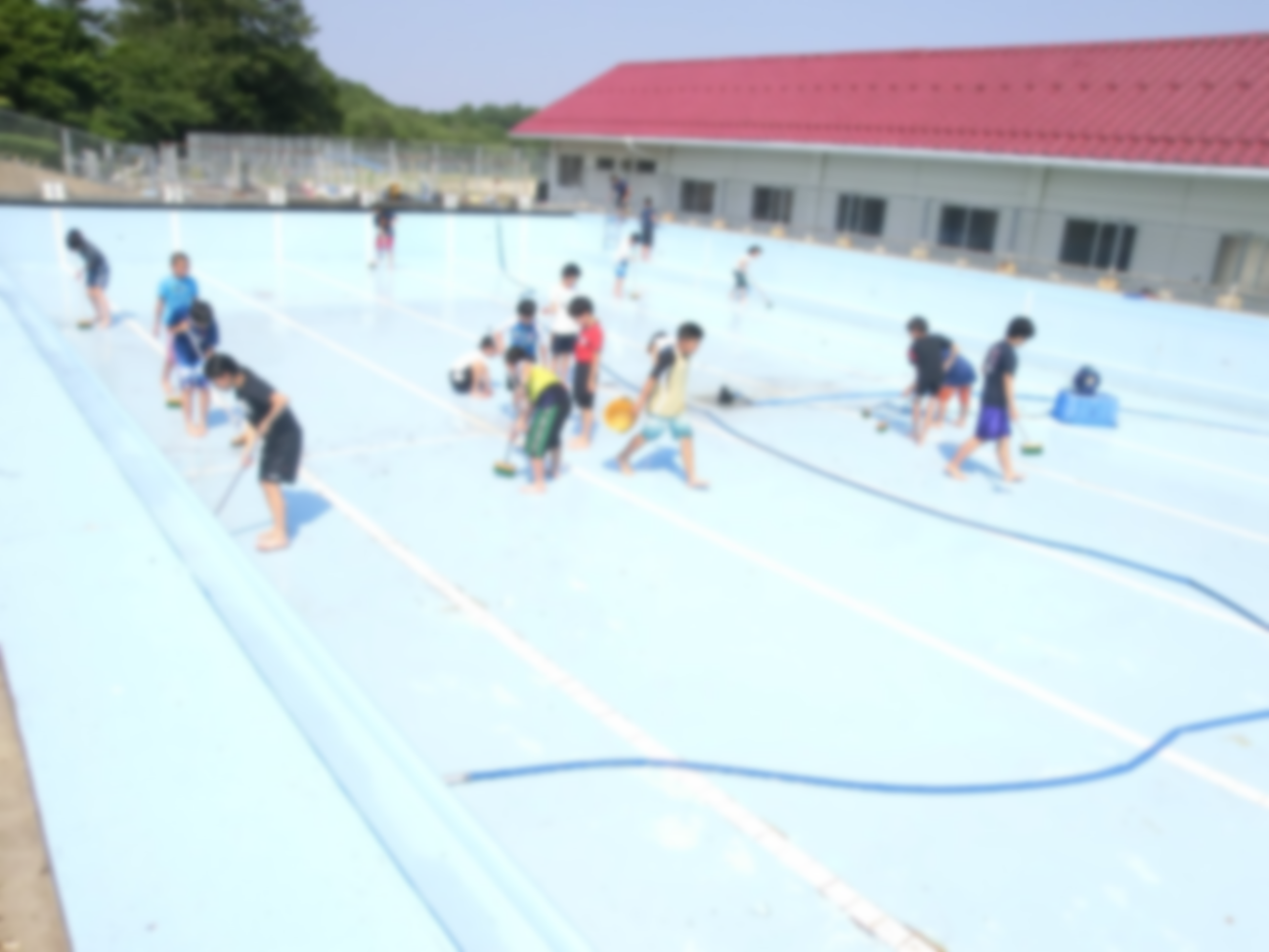 児童と教職員がプールの清掃をしている写真