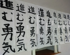 廊下の壁に「進む勇気」と半紙に書かれた作品が複数飾ってある写真