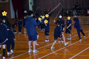 体育館で児童達が各チームに分かれて大縄跳びを行っている写真