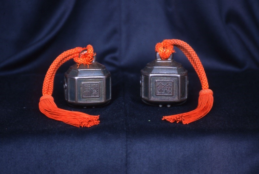 オレンジ色の取っ手がついた駅鈴が藍色の布の上に2つ置かれている写真