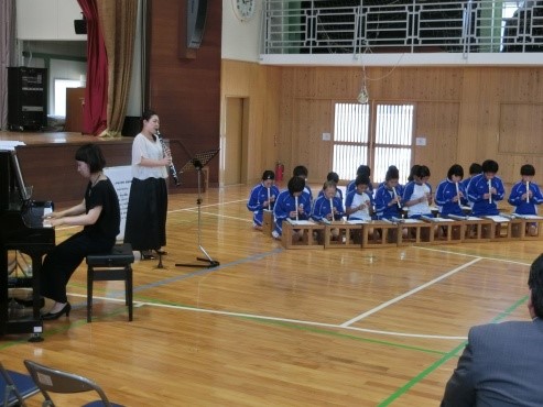 児童たちがクラリネット演奏者とともにリコーダーを合奏している写真