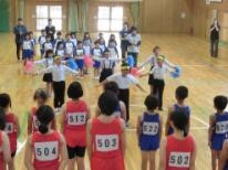 体育館でハチマキをした児童が選手にエールを送っている写真