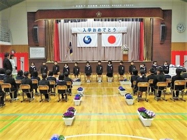 壇上に新入生が並び、来場者が着席する入学式の会場の写真
