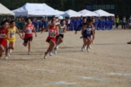 運動場で児童たちが全力で走って競っている写真