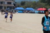 運動場で児童たちがリレーで走って競っている写真