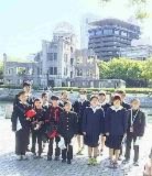 建物跡を背景に児童たちが並んでいる記念撮影の写真