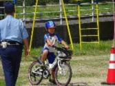 警察官の前で児童が自転車で一旦停止している写真