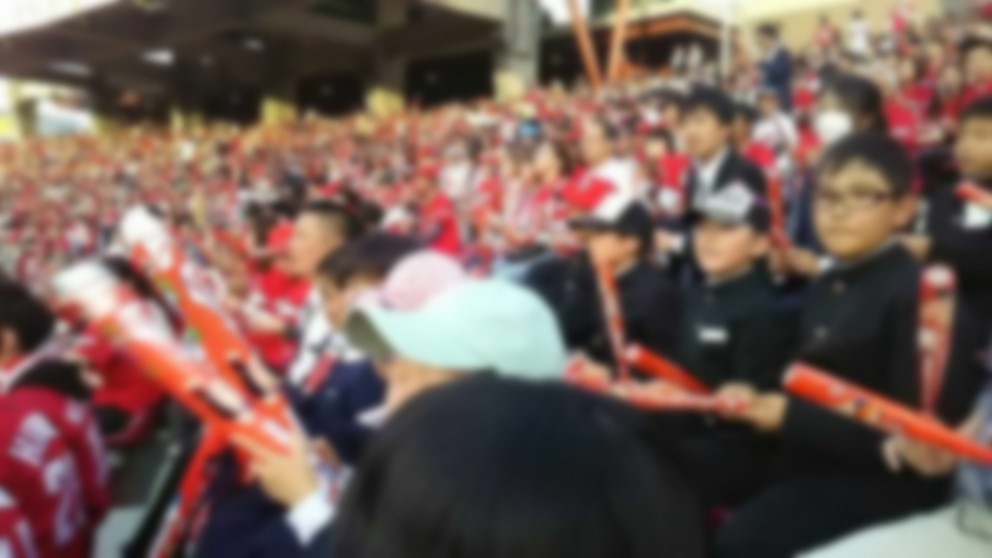 野球場の観客席で児童たちが応援道具を持って野球観戦をしている写真