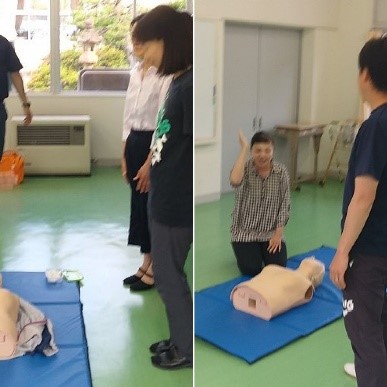 練習用の人形を前に救急救命法の指導を受けている保護者たちの写真