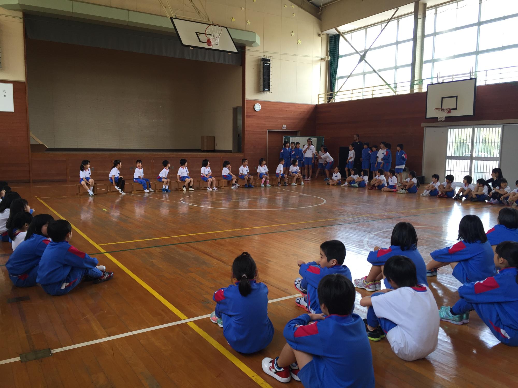 体育館に対面になって児童たちが向かい合って座っている写真