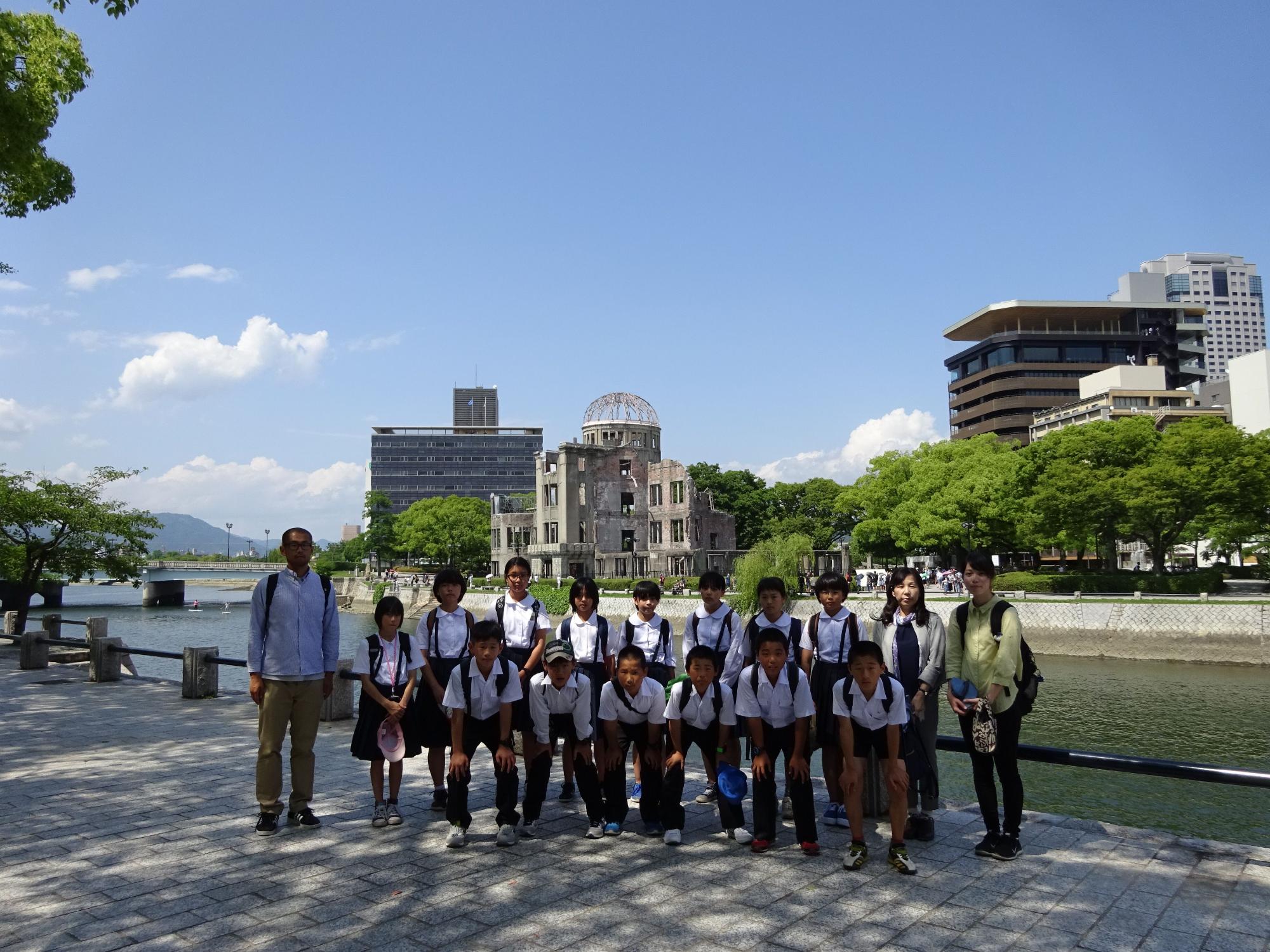 原爆ドームを背景に複数の児童と職員が整列して並んでいる写真