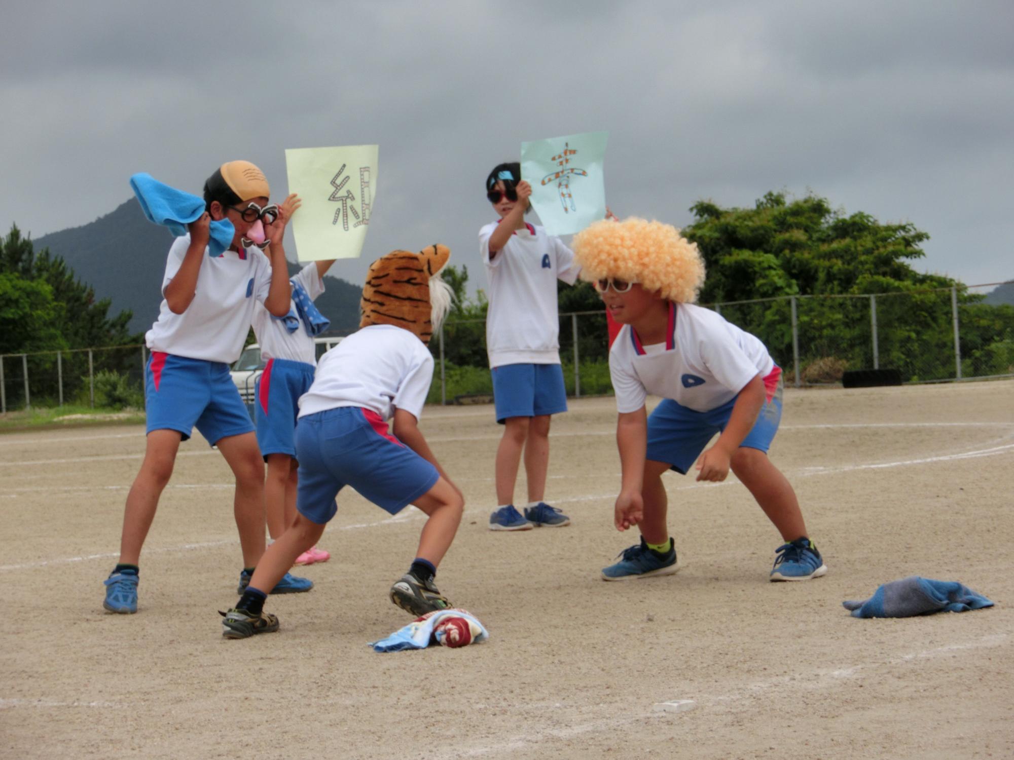 被り物を被った児童が相撲のようなポーズをとり向かい合っている写真