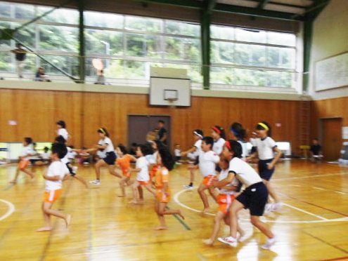 体育館で多くの児童や園児が体を動かしている写真