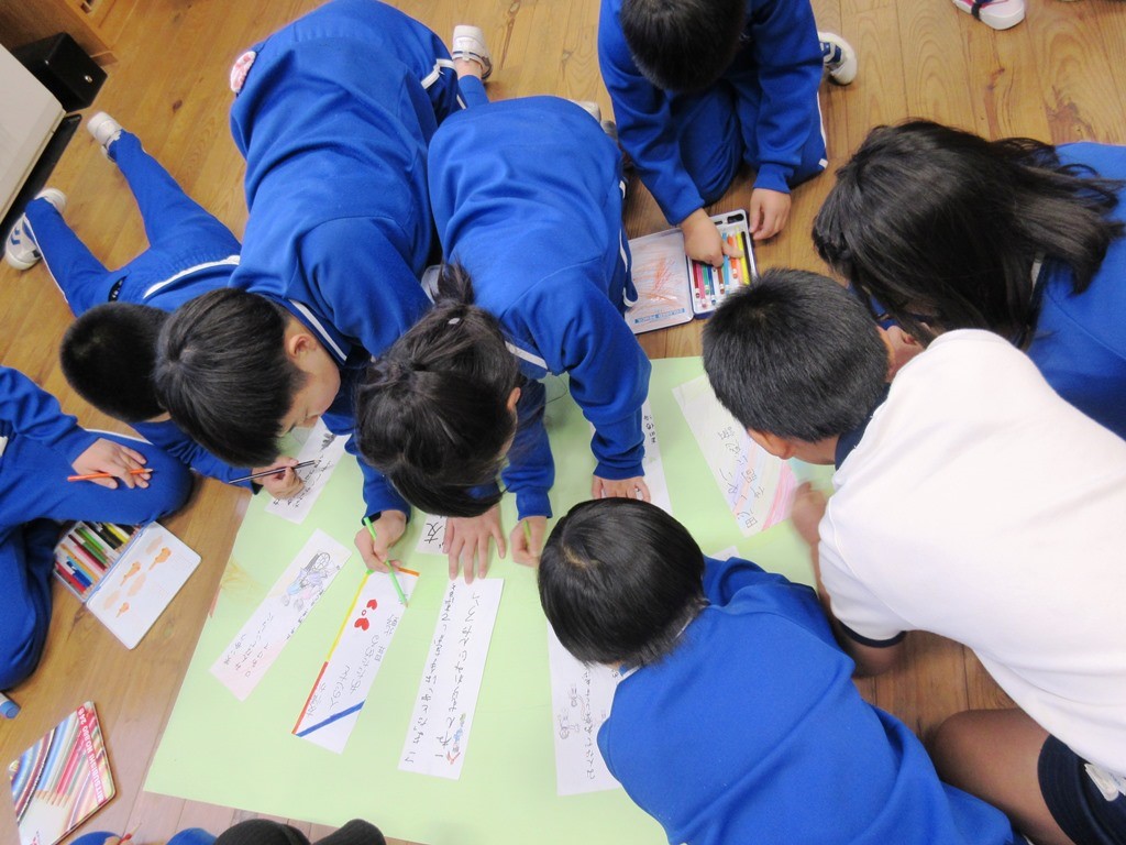 児童たちが標語を模造紙に張り付けてポスターを作っている写真