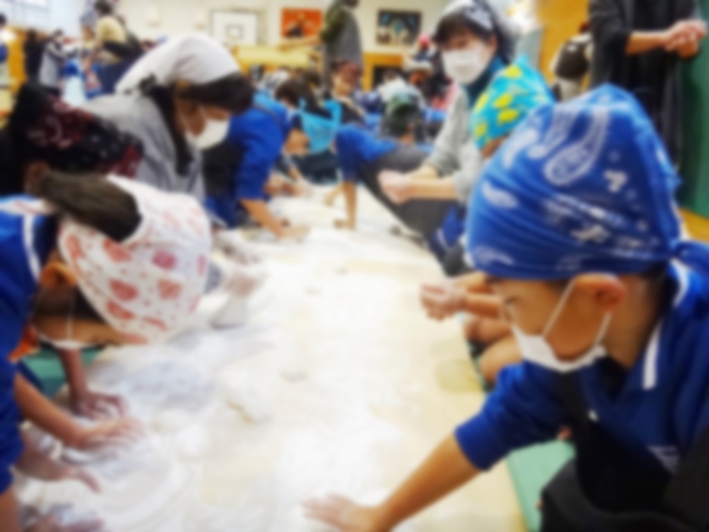 三角巾とマスクを着けた児童たちが搗いた餅を丸めている写真