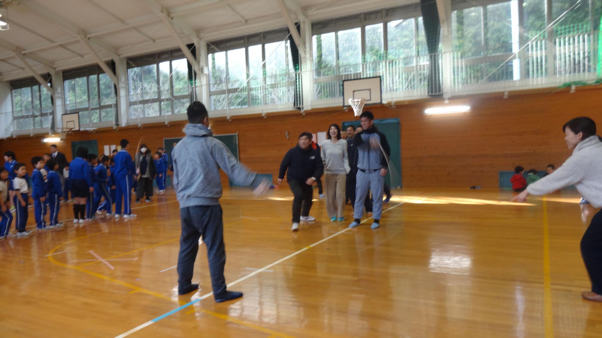 長縄跳びをしている先生たちを見ている児童たちの写真