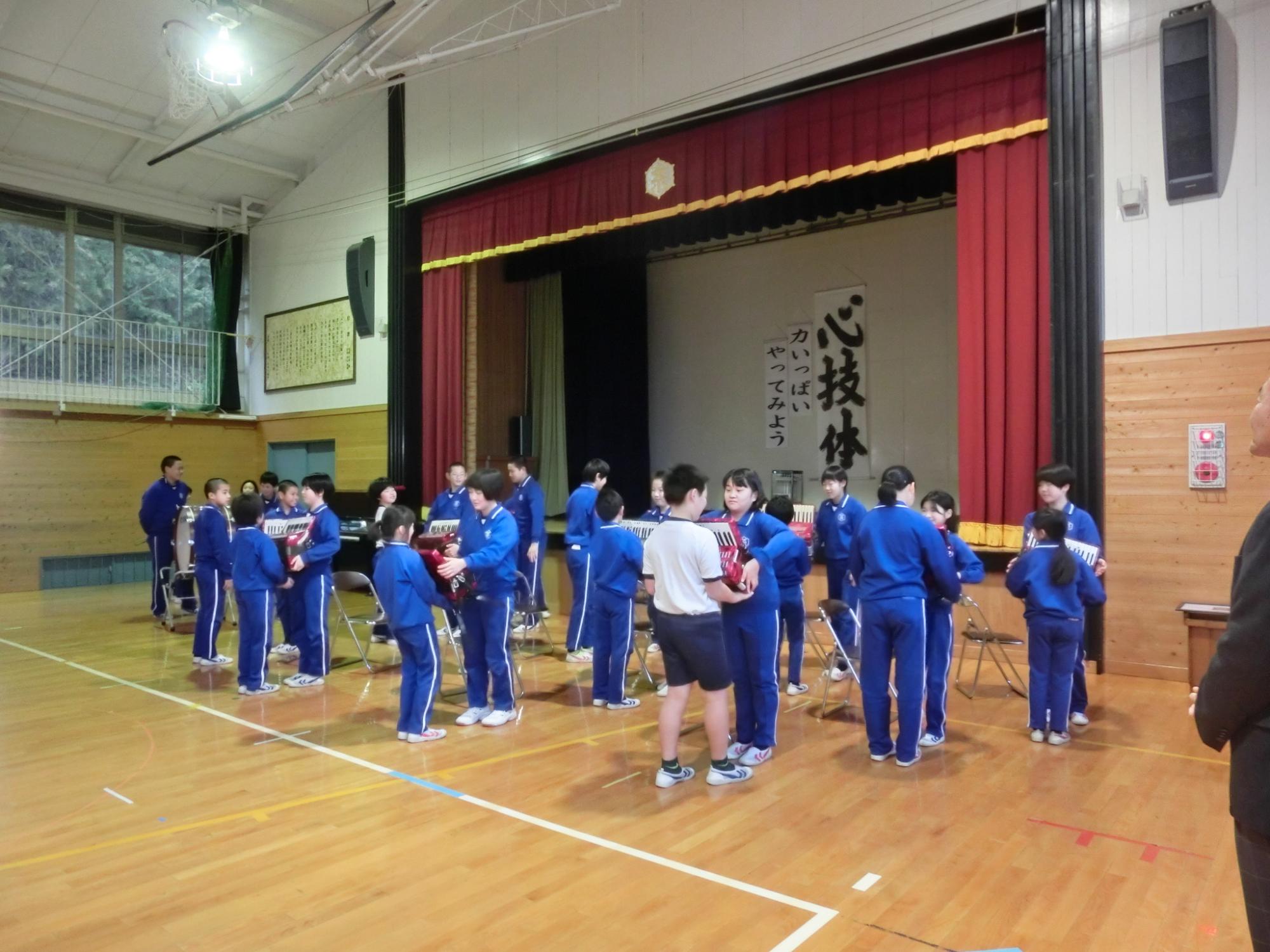 6年生の児童から5年生の児童に楽器を渡している写真