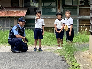 警察官と一緒に道路上の危険を指さし確認している児童の写真
