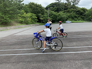 駐車場に作ったコースで児童たちが自転車に乗っている写真